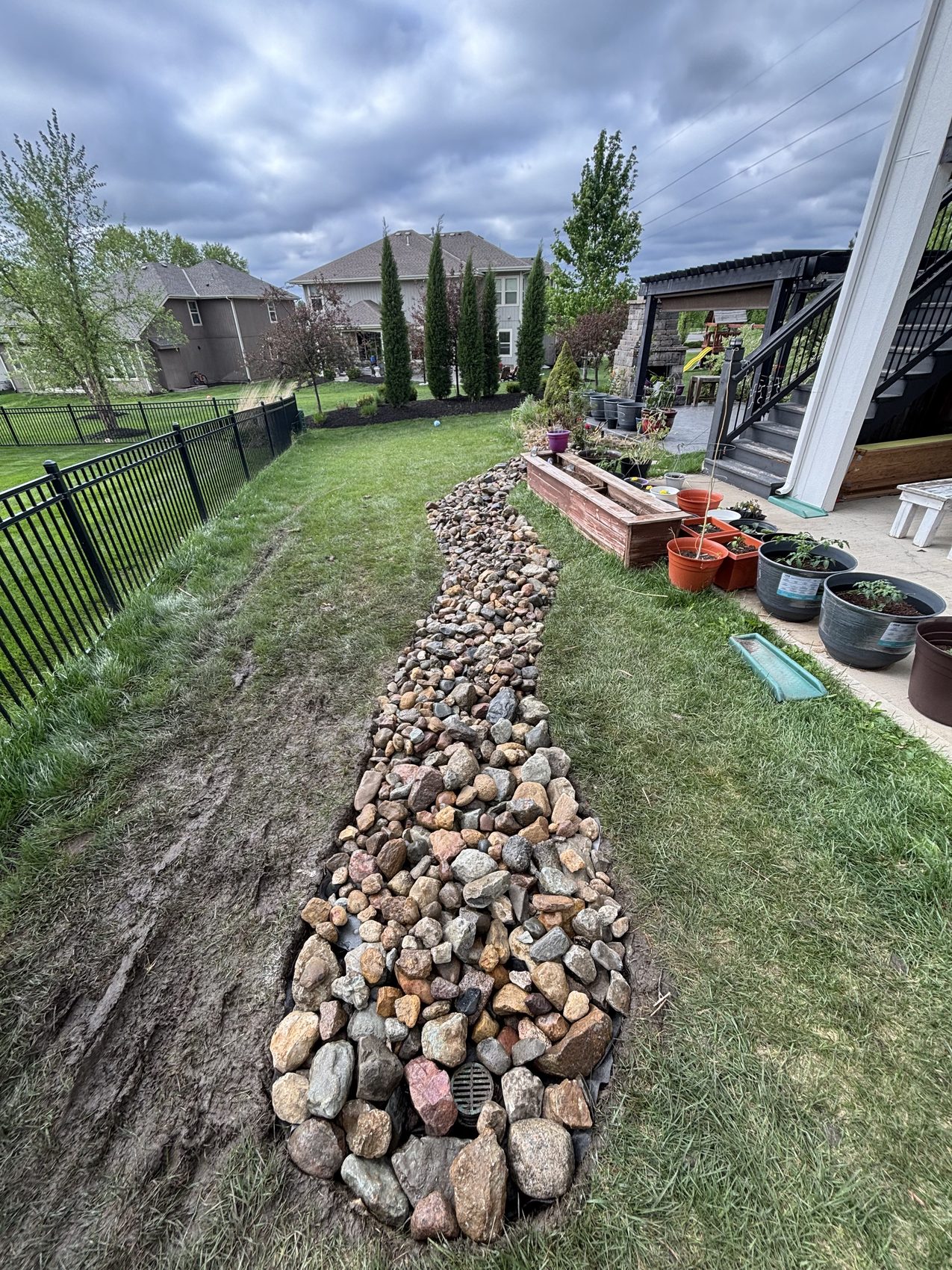 Finished premium river-rock drainage channel in a Kansas City backyard